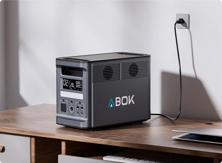 ABOK Ark2000 charging from a household wall outlet on a desk in a mobile home office scene
