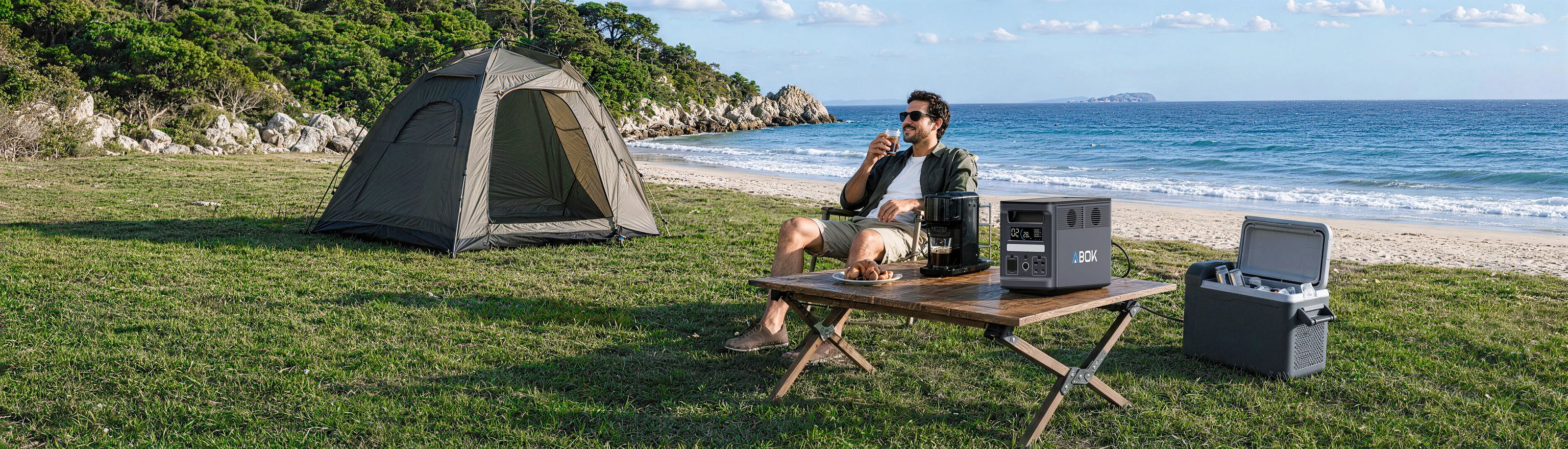 ABOK Ark2000 portable power station powering a coffee maker at a beach campsite.