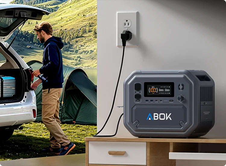 ABOK Ark2500 mobile split scene showing the portable power station at a campsite and charging from a household wall outlet